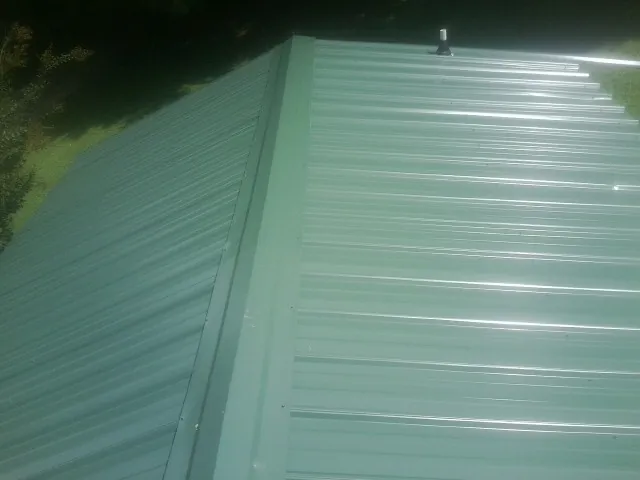 New green metal panels meeting at the ridge of a roof — Flat Roof Repair work by our crew in Troutville