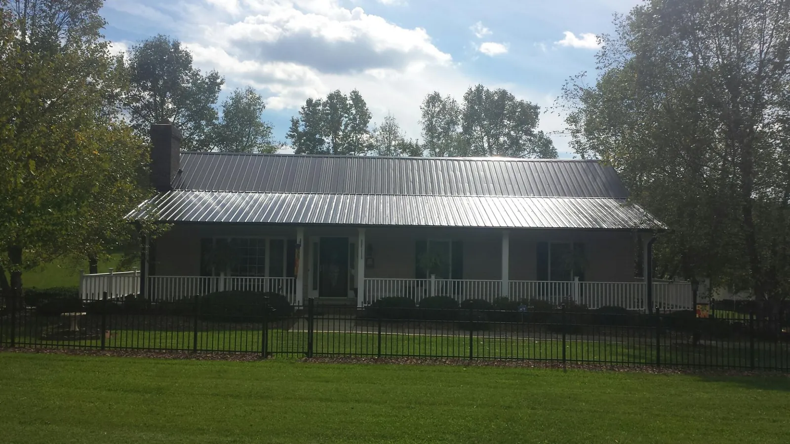Gray metal roof on a brick ranch with a full width front porch — Gutter Guard Installation work by our crew in Troutville