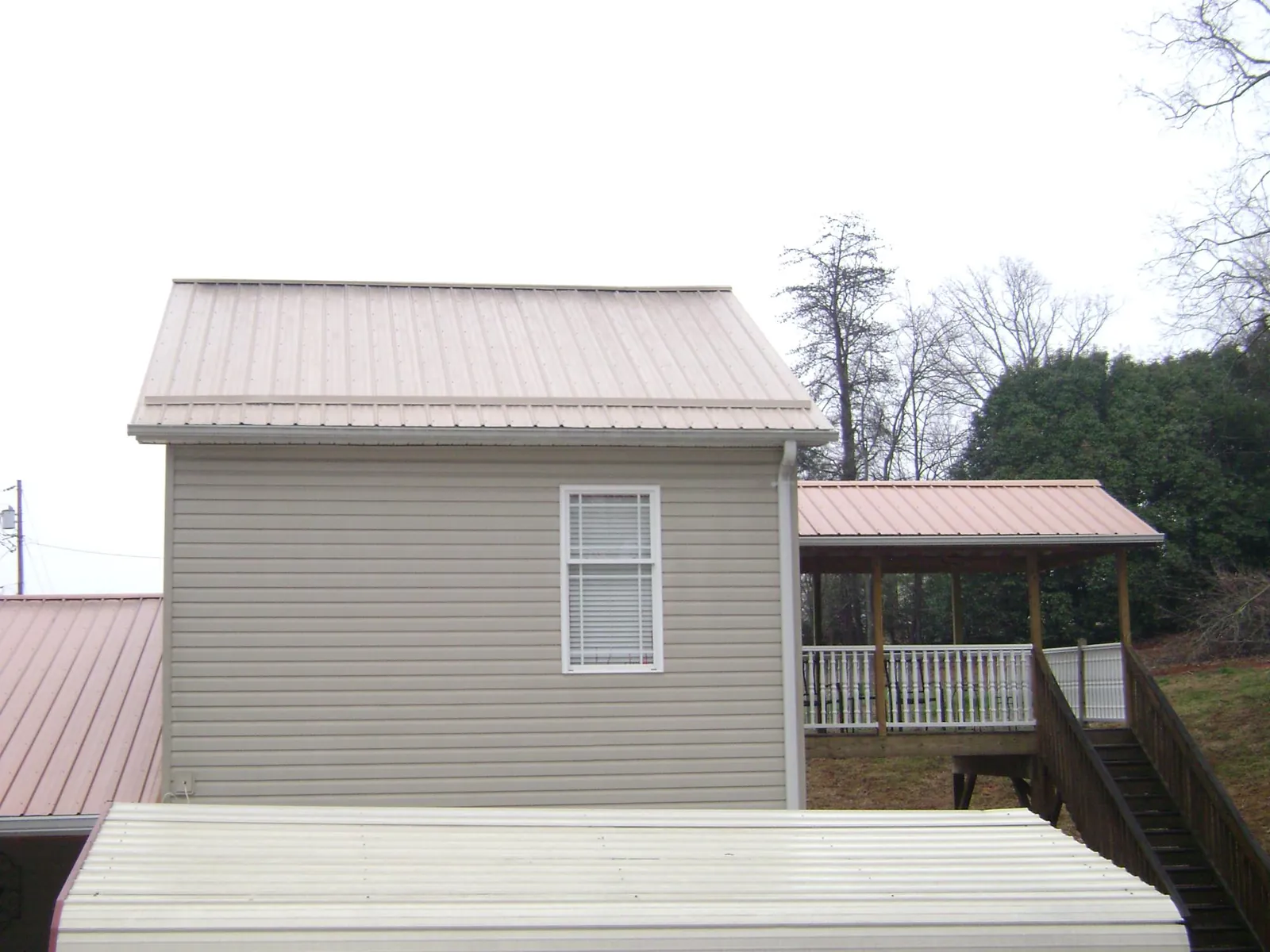 Tan metal roofs on a two story addition and attached porch, from a Roof Replacement job in Troutville